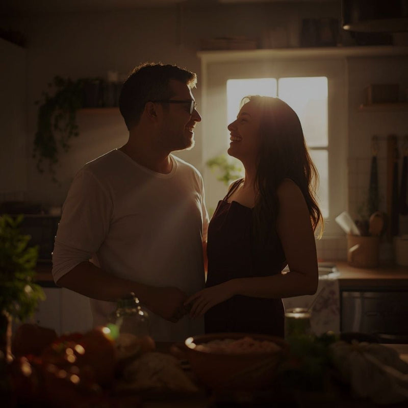 Intimate photo of a man and woman in a dimly lit kitchen staring at one another with love