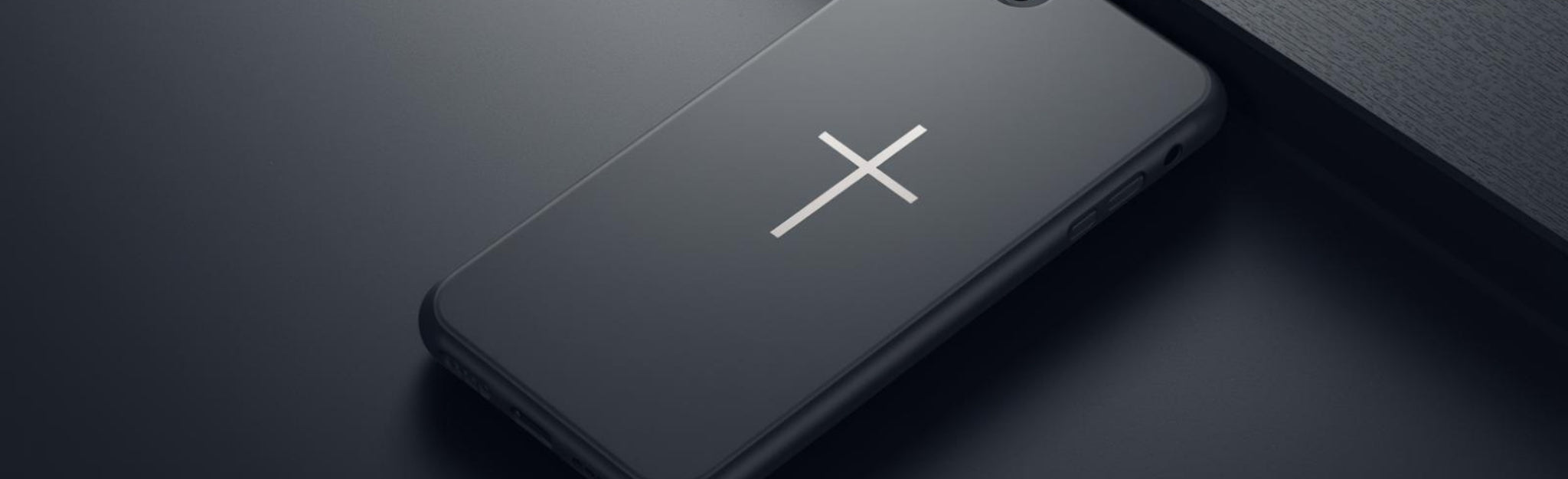 Black phone case with golden cross on the cover sitting on a black counter
