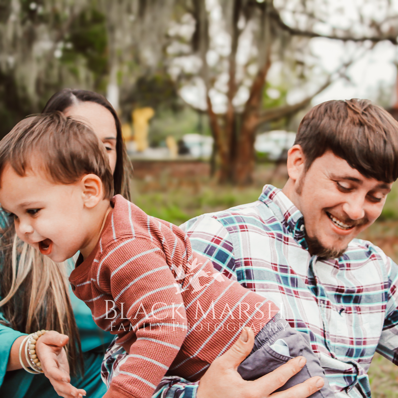 Photograph of father and son laughing with mother in background